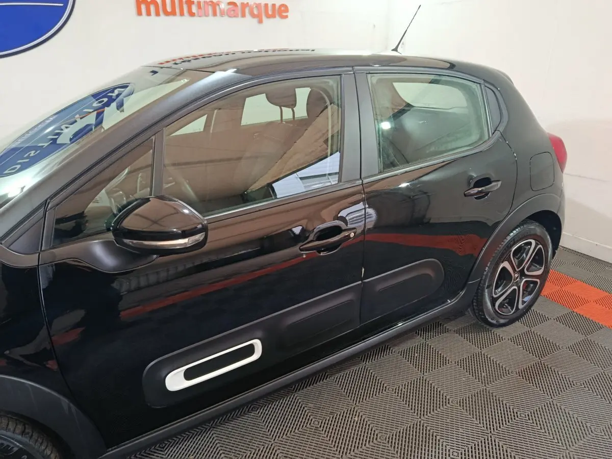 Profil côté gauche d'une Citroën C3 noire 2024 avec protections latérales blanches et jantes stylisées.