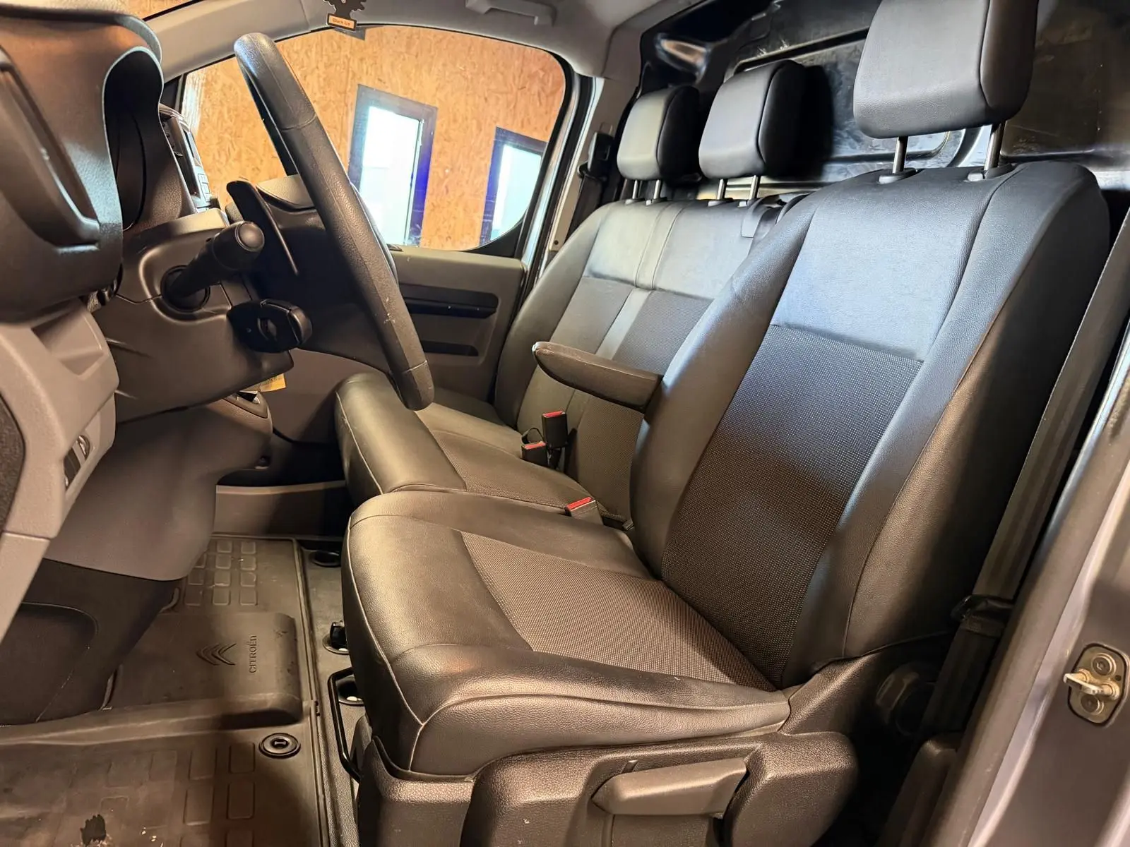 Vue intérieure côté conducteur du Citroën Jumpy gris 2022, montrant les sièges en cuir et le volant.