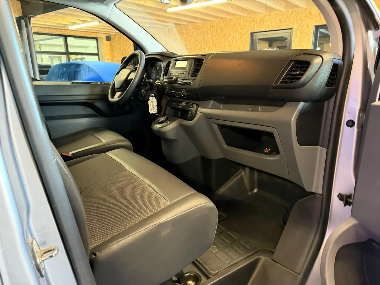 Vue intérieure côté conducteur du Citroën Jumpy gris 2022, montrant le tableau de bord et la banquette avant.