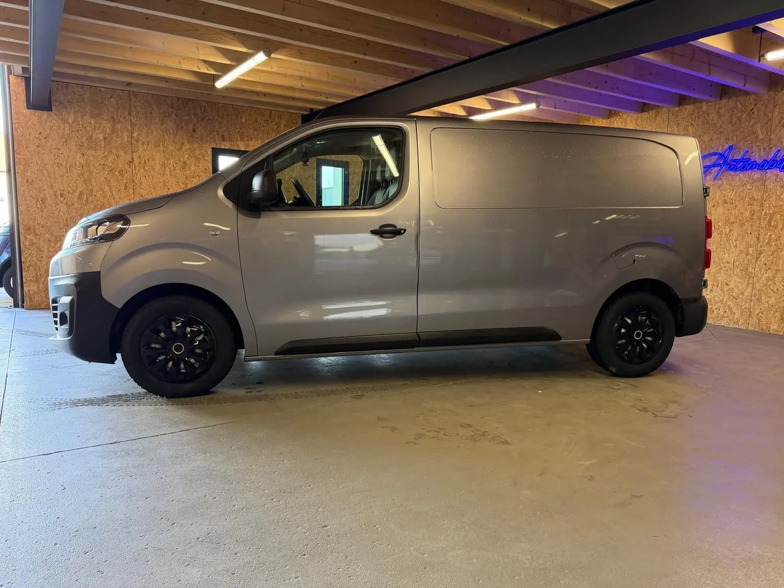 Vue de profil côté gauche d’un Citroën Jumpy gris métallisé 2022 avec porte latérale et jantes noires.