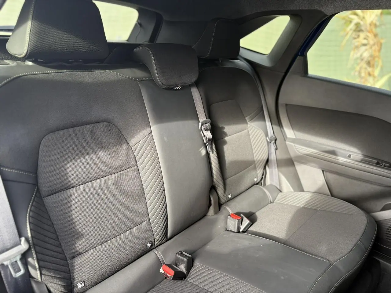 Vue latérale intérieure sur la banquette arrière noire du Renault SYMBIOZ E-Tech Full Hybrid 2025 avec ceintures et appuie-têtes.