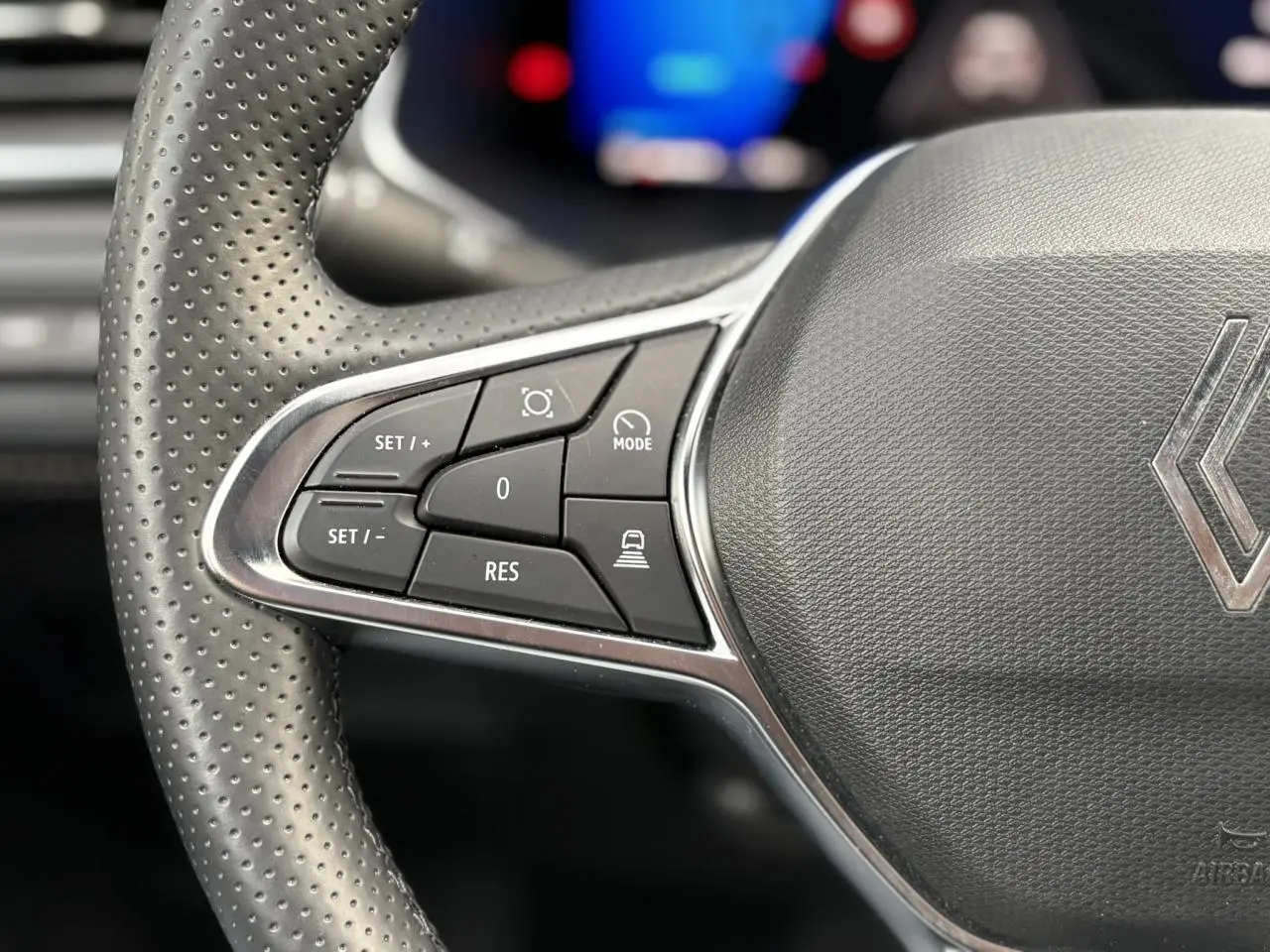 Gros plan sur les commandes à gauche du volant perforé gris foncé du Renault Symbioz 2025 hybride.