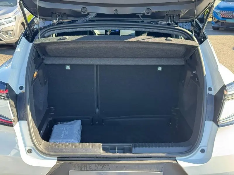 Coffre ouvert vu de l'arrière d'un Renault Captur blanc nacré 2025, avec cache-bagages et tapis de sol visible.
