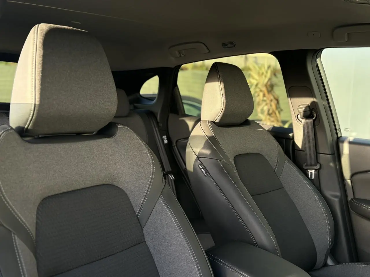 Vue intérieure sur les sièges avant gris et noirs du Nissan Qashqai III e-Power avec accoudoir central et ceinture côté droit.
