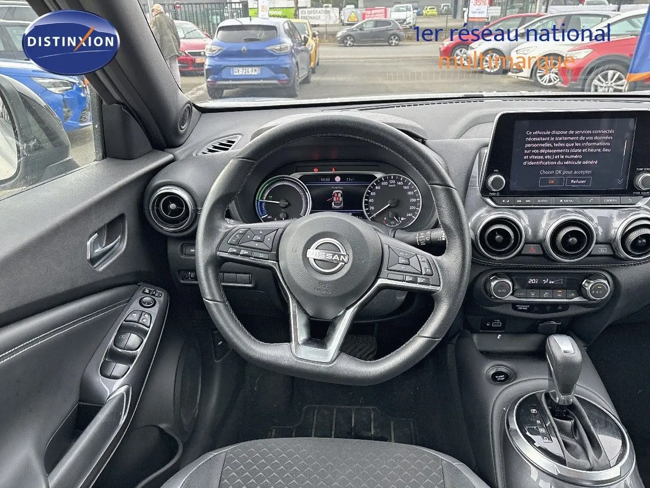 Vue intérieure du poste de conduite du Nissan Juke gris perle 2024, avec volant multifonction et écran tactile central.