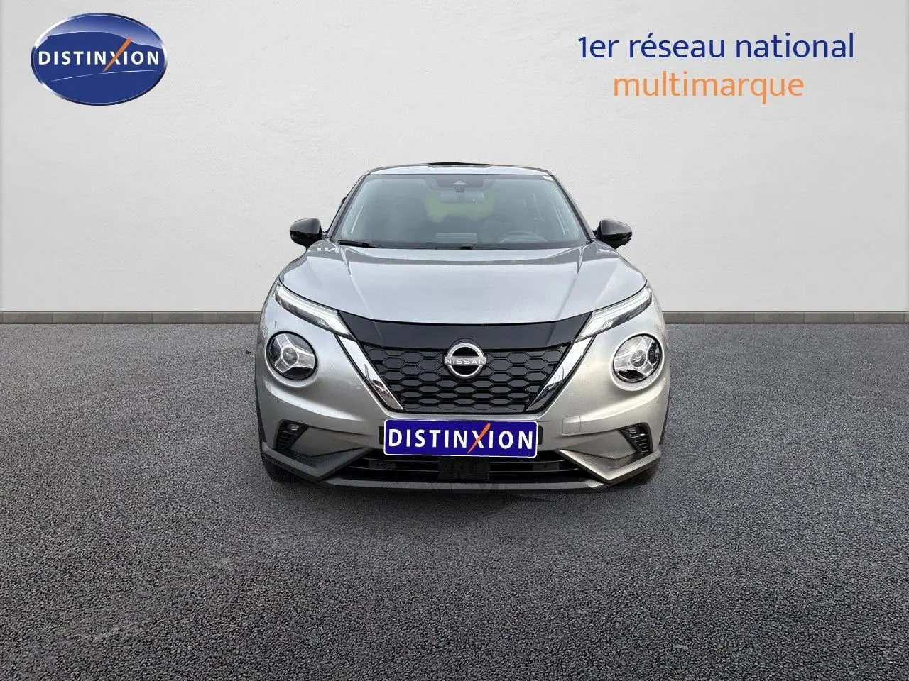 Vue frontale d'un Nissan Juke 1.6 HEV gris perle métal avec calandre noire et phares ronds distinctifs.