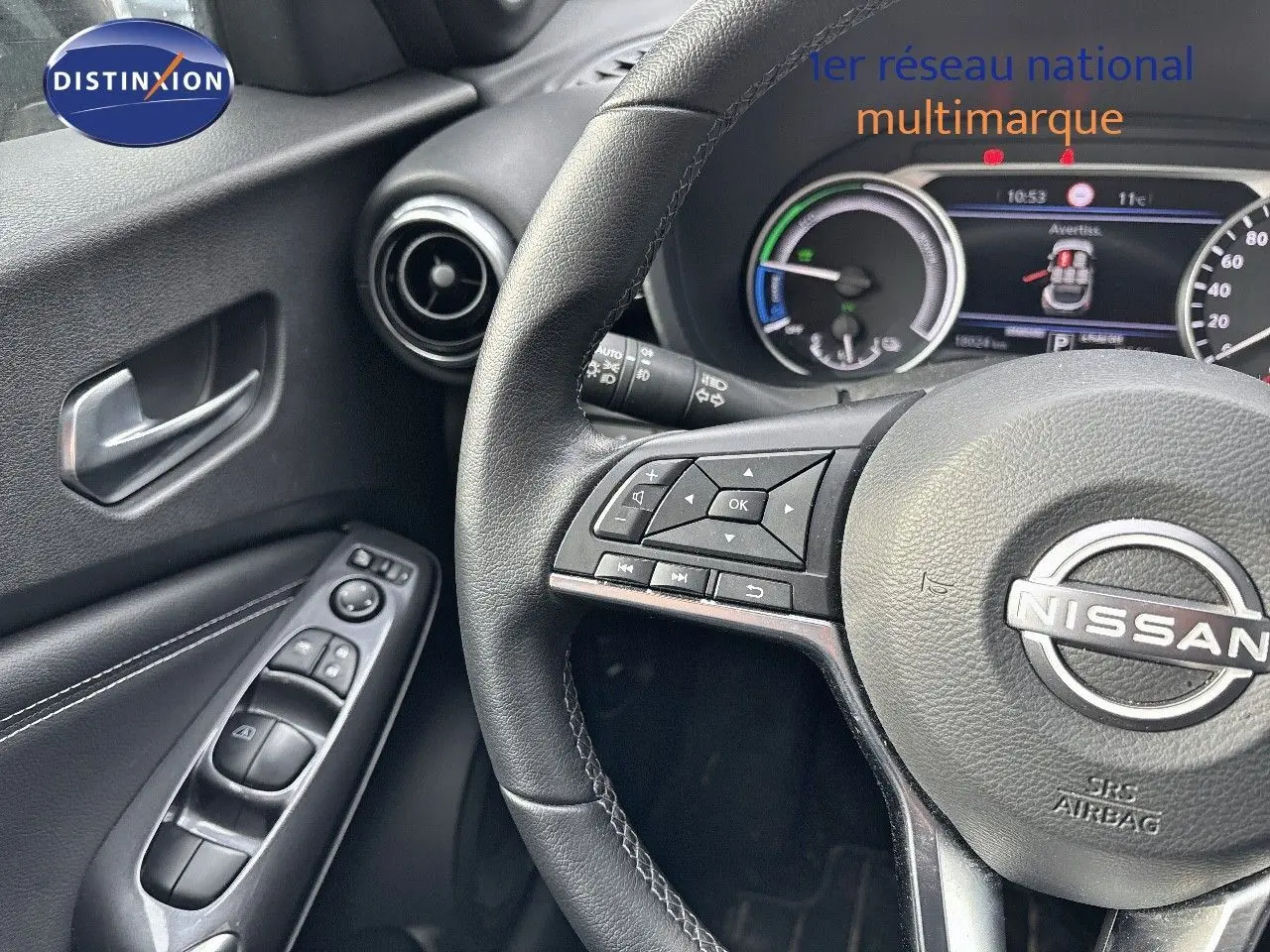 Vue rapprochée du volant et de la portière côté gauche du Nissan Juke gris perle 2024 avec commandes intégrées.