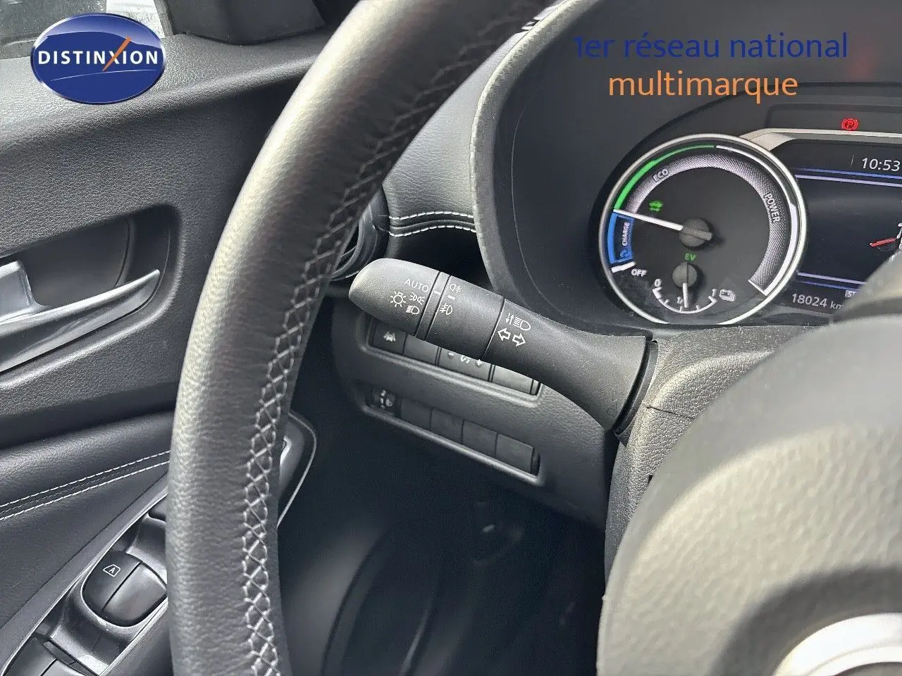 Vue rapprochée du tableau de bord et volant noir du Nissan Juke gris perle hybride avec compteur digital et commandes intégrées.