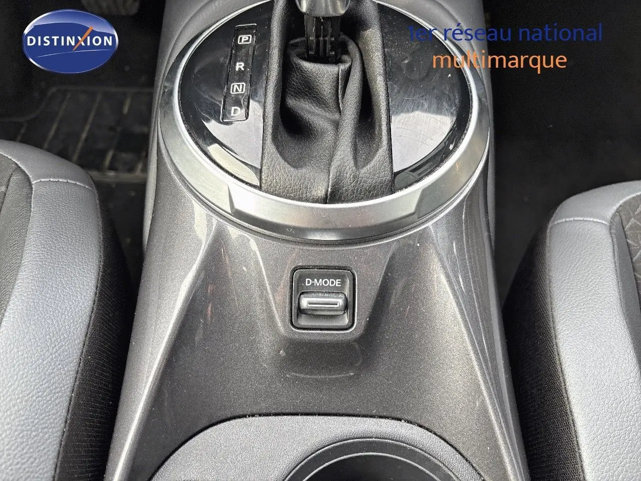 Gros plan sur la console centrale grise perle métallisée du Nissan Juke 2024, avec levier de boîte auto et bouton D-MODE.