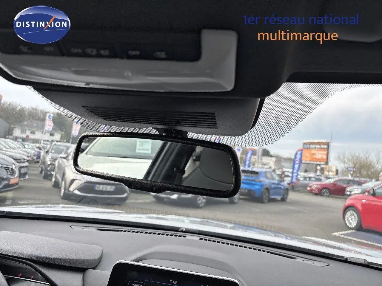 Vue intérieure du tableau de bord et rétroviseur d'un Nissan Juke gris perle métal 2024 en concession.