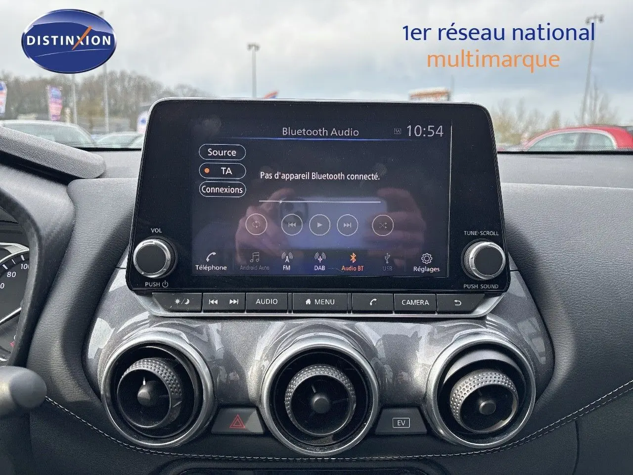 Vue rapprochée de la console centrale du Nissan Juke 2024 gris perle, avec écran tactile et commandes circulaires d’aération.