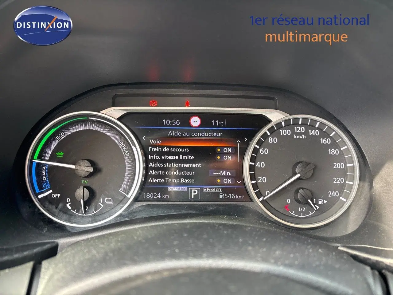 Tableau de bord du Nissan Juke 2024 gris perle, affichant l'écran d'aide au conducteur et compteurs vitesse et énergie.