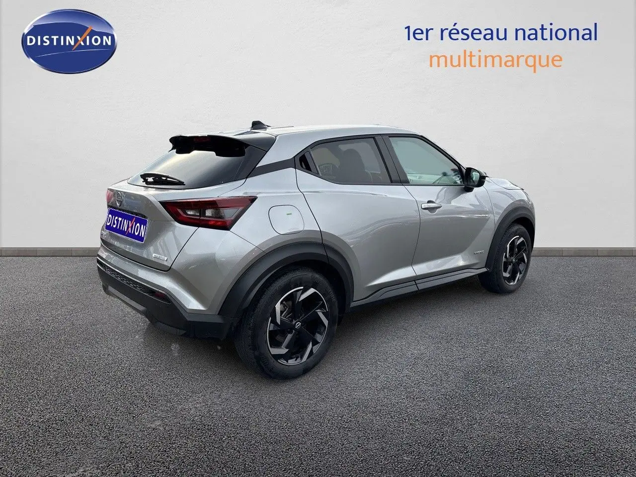 Nissan Juke 1.6 HEV gris perle métal, vue 3/4 arrière côté droit, avec jantes noires et toit noir contrasté.
