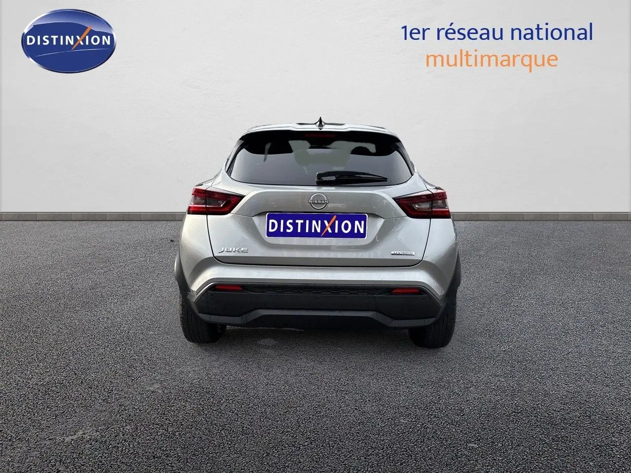 Vue arrière d'un Nissan Juke 2024 gris perle métal, version hybride N-Connecta avec logo Distinxion visible.