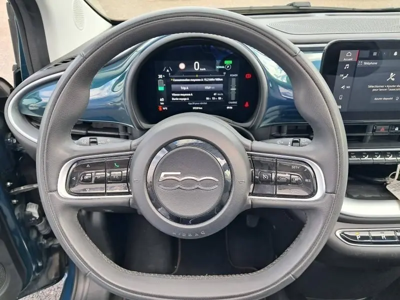 Vue frontale du volant de la Fiat 500C 118 cv icone 2021 vert foncé métal avec tableau de bord numérique et commandes intégrées.
