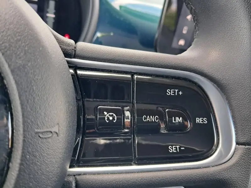 Gros plan sur les commandes de régulateur de vitesse au volant d'une FIAT 500C 118 cv icone vert foncé métal 2021 électrique.