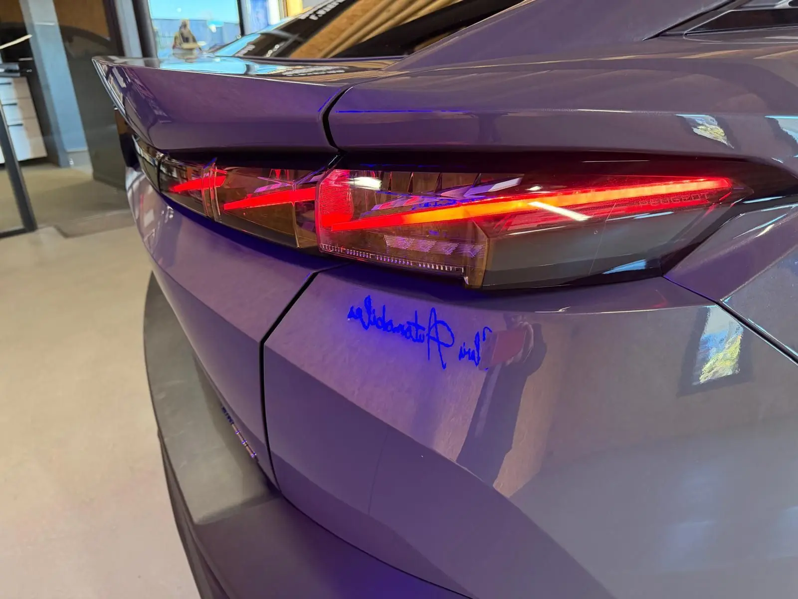 Gros plan sur le feu arrière droit rouge d'une Peugeot 408 gris métallisé, avec reflets intérieurs et lignes anguleuses.