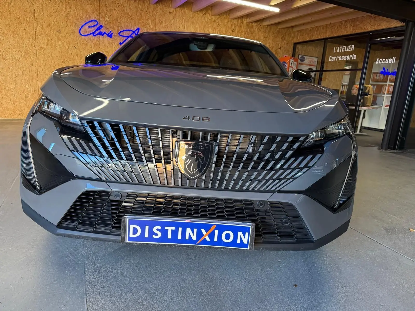 Vue de face d'une Peugeot 408 gris métallisé avec calandre verticale distinctive et logo lion noir brillant.