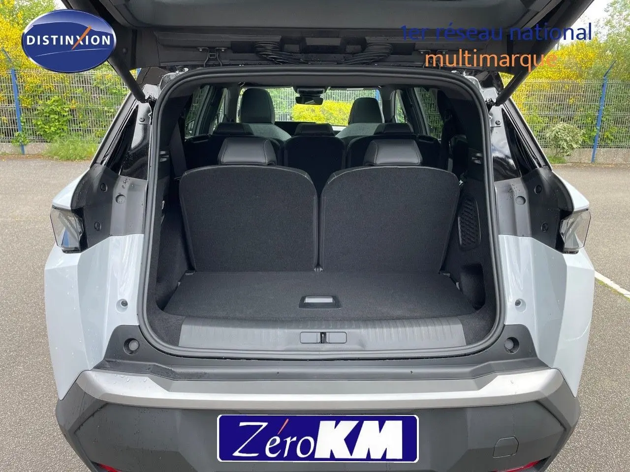 Vue arrière ouverte du Peugeot 5008 HYBRID 136CH GT blanc Okenite avec toit noir, montrant le coffre et les sièges arrière.