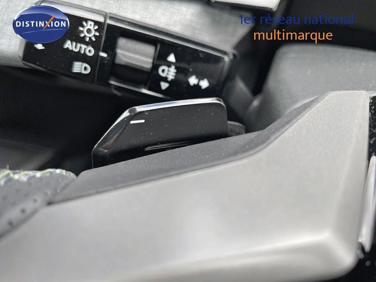 Gros plan sur la palette de changement de vitesse noire du Peugeot 5008 Hybrid 2025, avec commandes d'éclairage en arrière-plan.