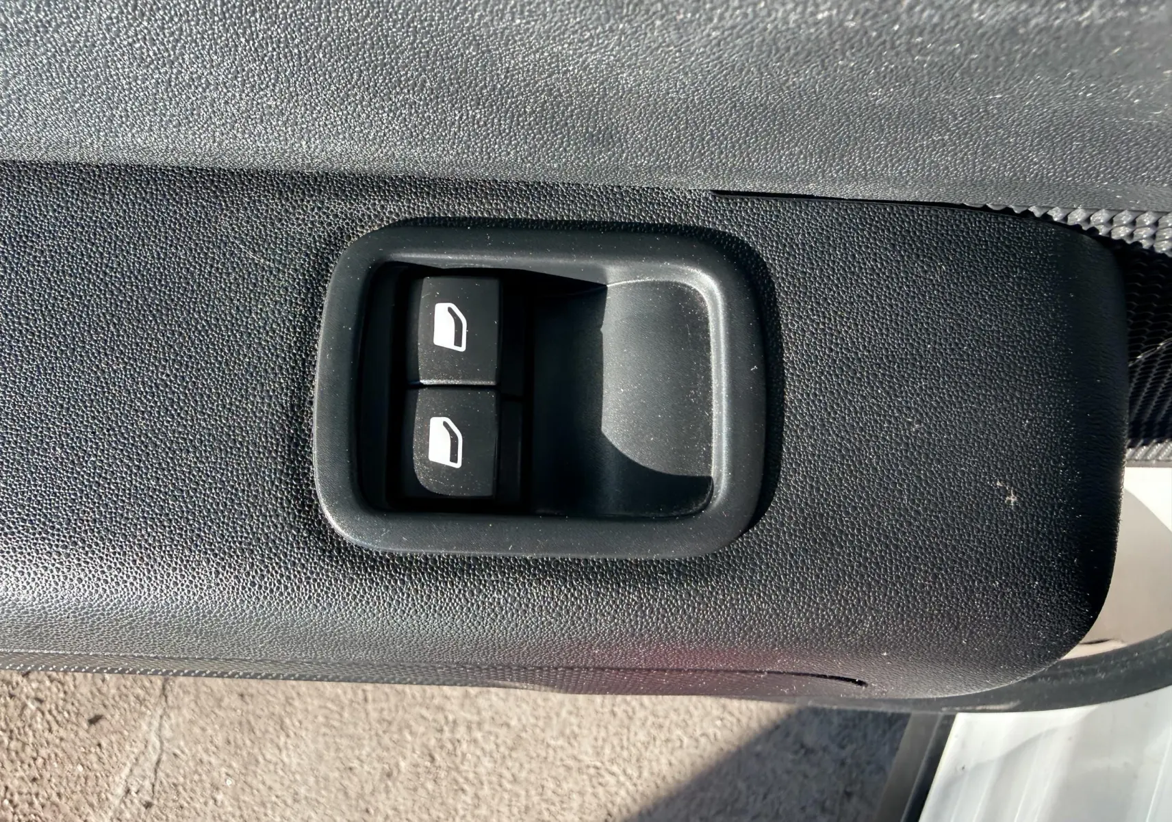 Gros plan sur les commandes de lève-vitres noirs intégrées à la porte côté gauche d'une Citroën C3 blanche.