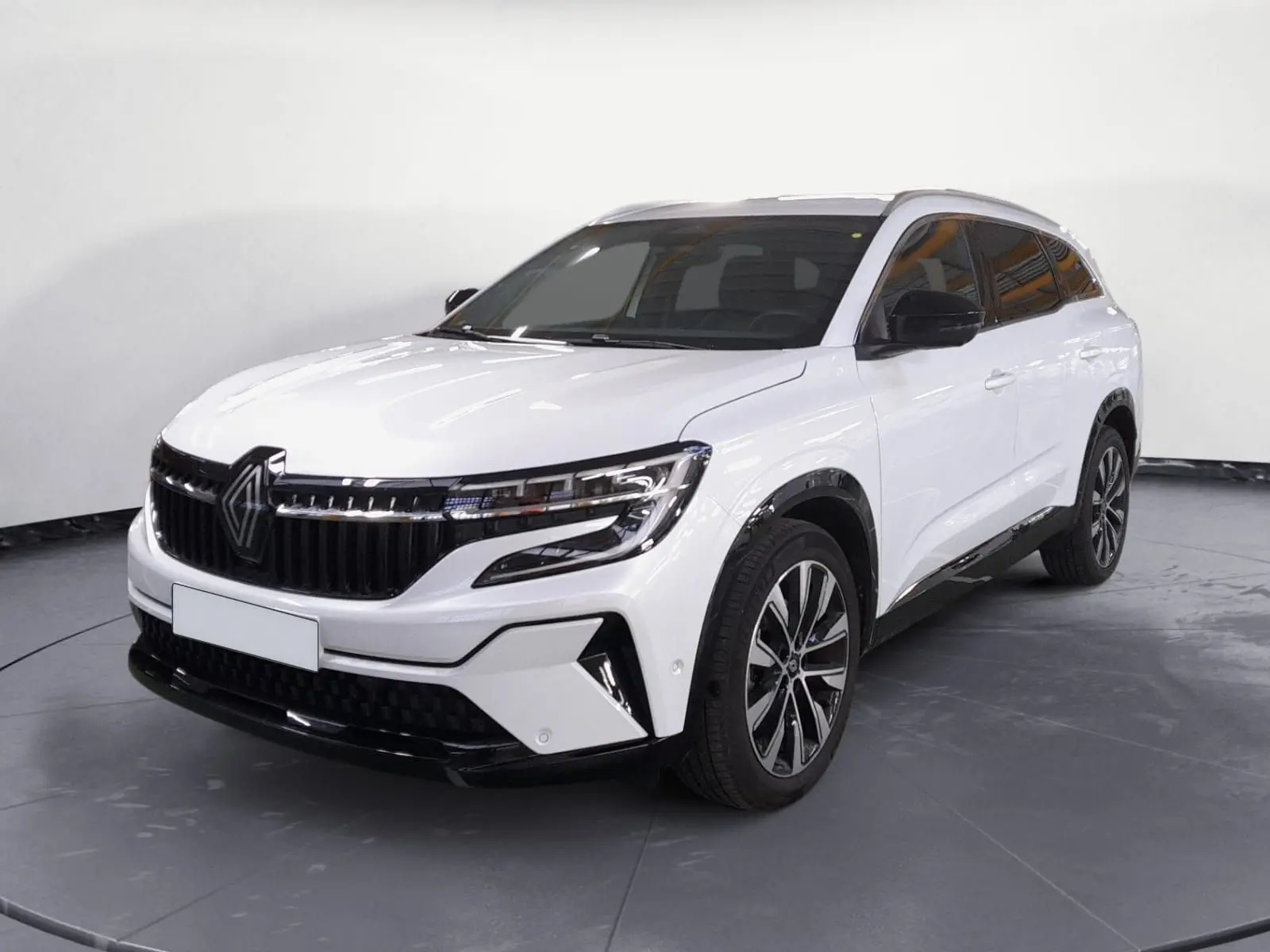 Renault Espace blanc nacré en 3/4 avant droit avec jantes alliage noires et calandre marquée noire brillante.