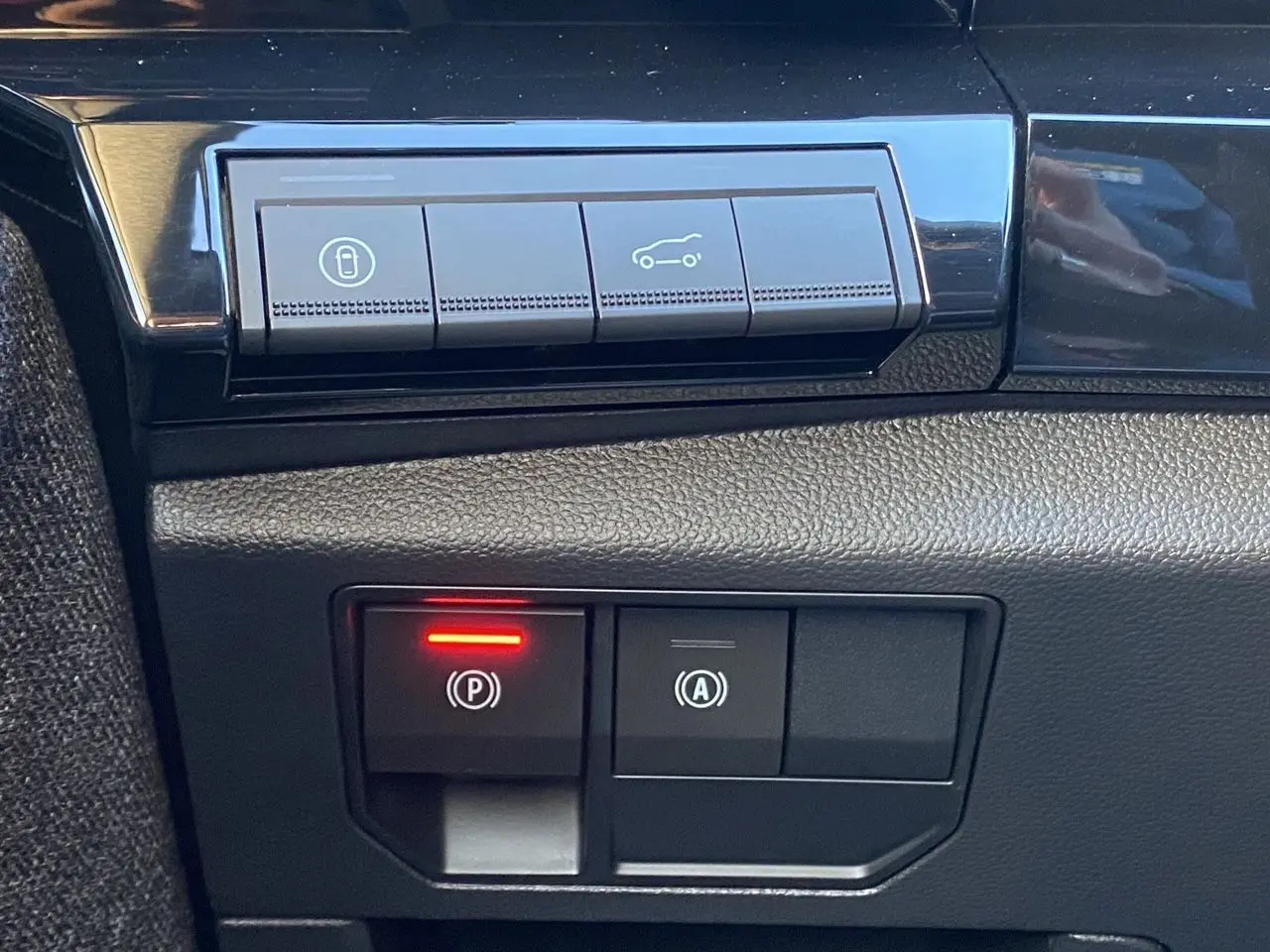 Gros plan sur les commandes noires du tableau de bord du Renault Espace, avec témoin rouge actif sur frein de parking.