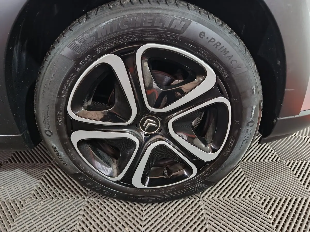 Gros plan sur la roue avant droite gris clair d'une Citroën C3 2024 avec jante noire et argentée au design distinctif.