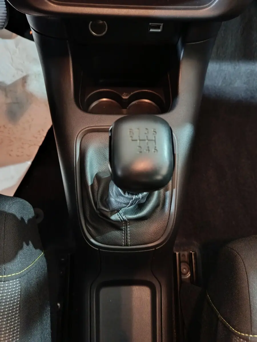 Vue plongeante sur le levier de vitesses manuel noir de la Citroën C3 2024, avec console centrale et porte-gobelets.