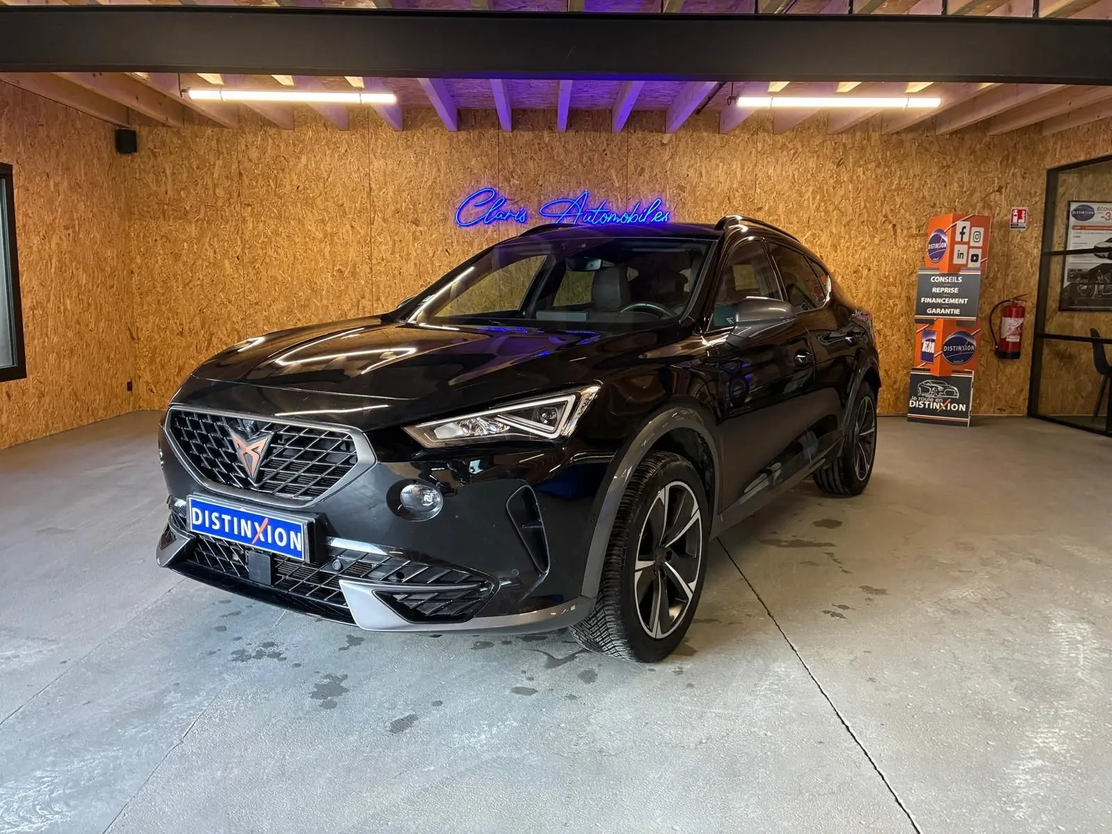 Vue 3/4 avant d'un CUPRA Formentor noir 2022 avec jantes alu et calandre au logo cuivre dans un showroom.