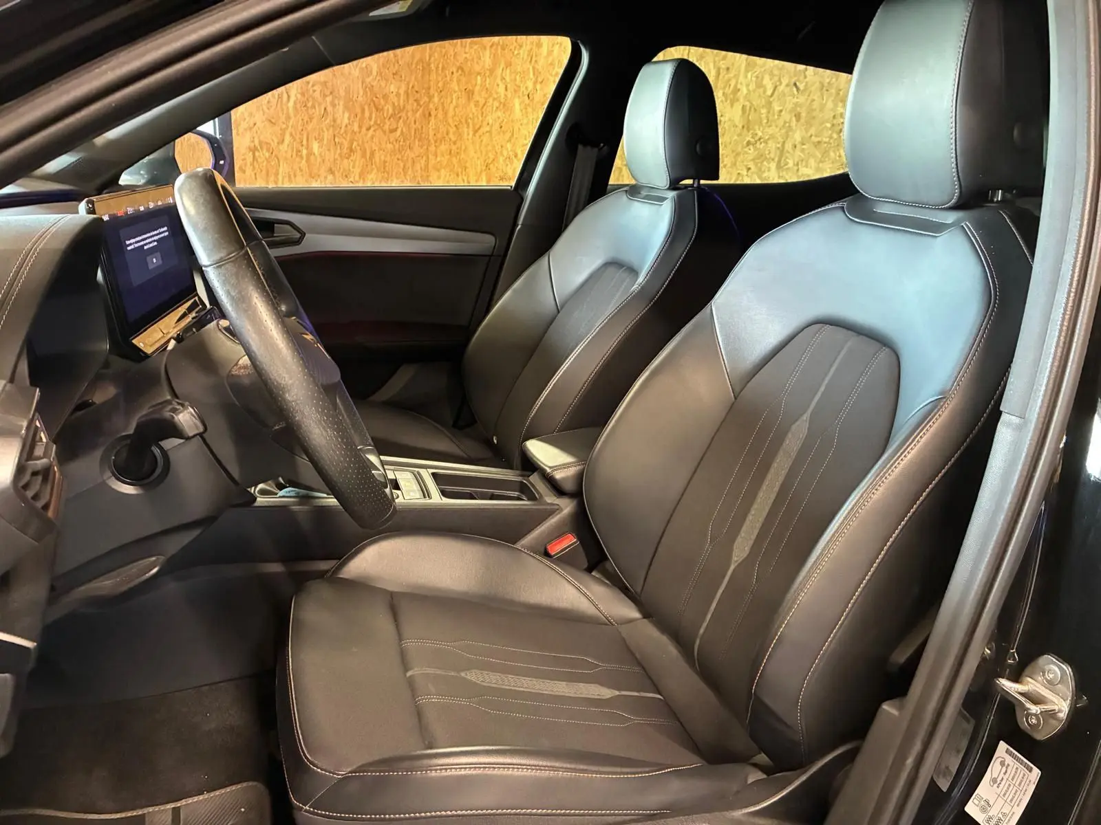 Vue intérieure côté conducteur de la CUPRA Formentor 2.0 TDI 150 V 2022 avec sièges noirs en tissu et cuir, tableau de bord moderne.