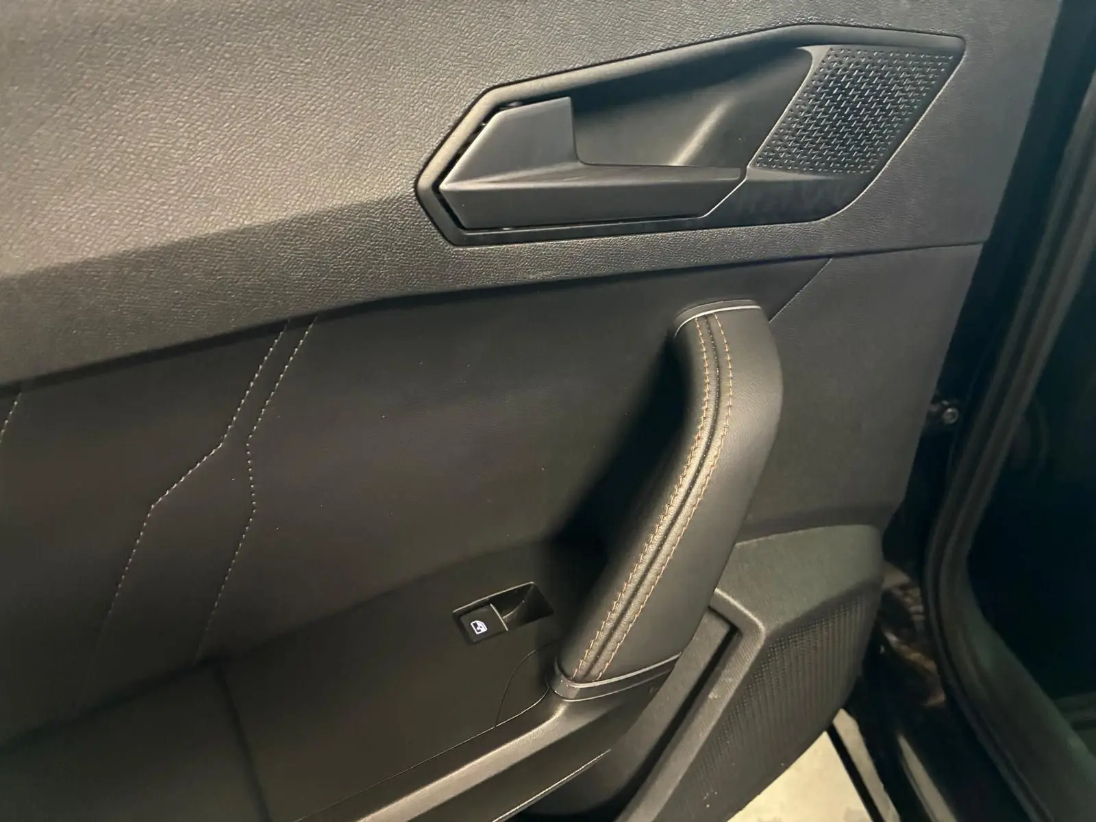 Gros plan sur la poignée intérieure côté gauche de la porte noire du CUPRA Formentor 2.0 TDI avec surpiqûres cuivrées.