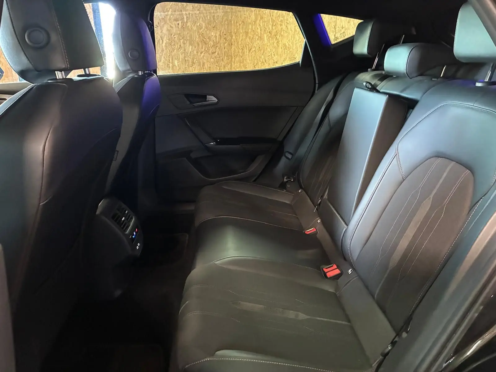 Vue intérieure arrière droite du CUPRA Formentor noir, montrant les sièges en tissu et cuir avec accoudoir central relevé.