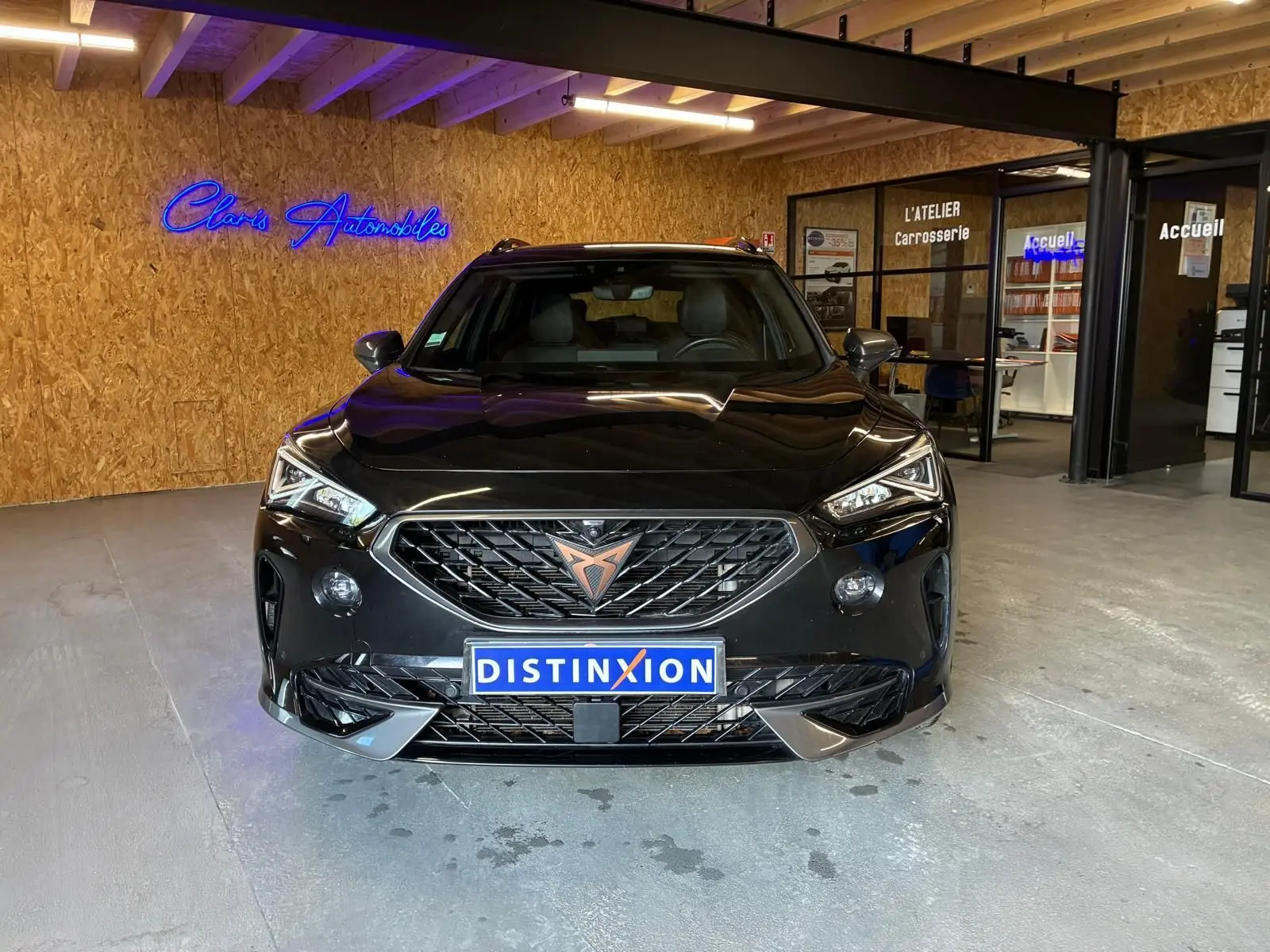 Vue frontale d'une CUPRA Formentor noire 2022 avec calandre marquée et logo cuivré, dans un garage moderne.
