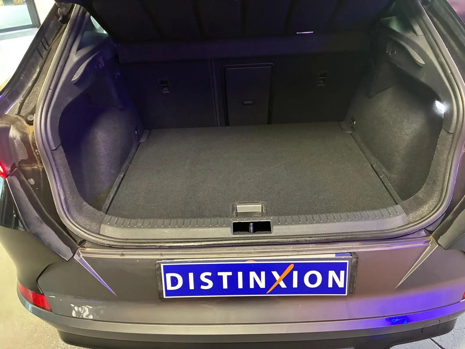 Coffre ouvert vu de l'arrière d'une CUPRA Formentor noire avec intérieur de coffre sombre et plaque Distinxion.