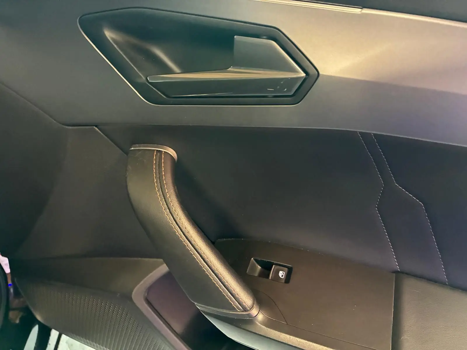 Détail de la poignée de porte côté passager du CUPRA Formentor noir avec surpiqûres cuivrées et bouton de commande de vitre.