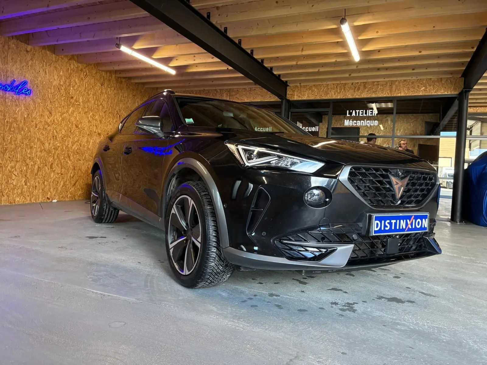 Vue 3/4 avant droite d'un CUPRA Formentor noir 2022 avec jantes alu et calandre distinctive en intérieur d'atelier.