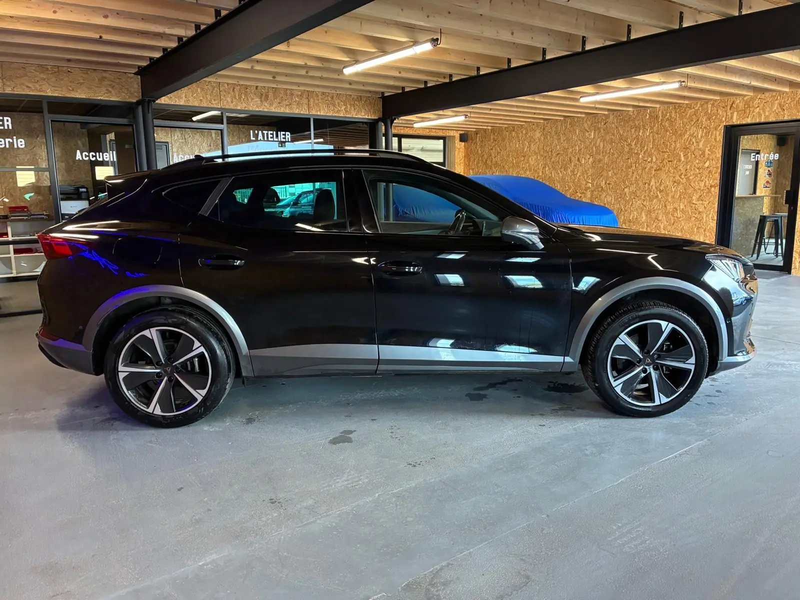 Vue de profil côté gauche d'un CUPRA Formentor noir 2022 avec jantes alu et entourage de vitres noir piano.