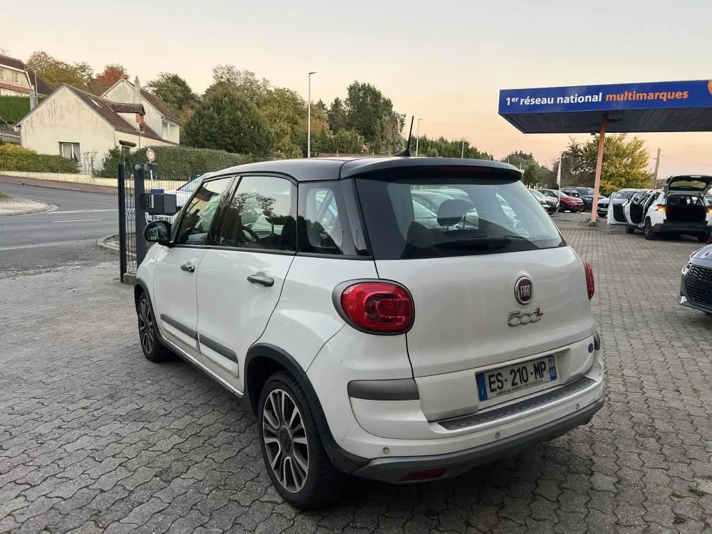 Vue 3/4 arrière droite d'une FIAT 500L 2017 bi-color blanc avec toit noir, stationnée sur un parking pavé.