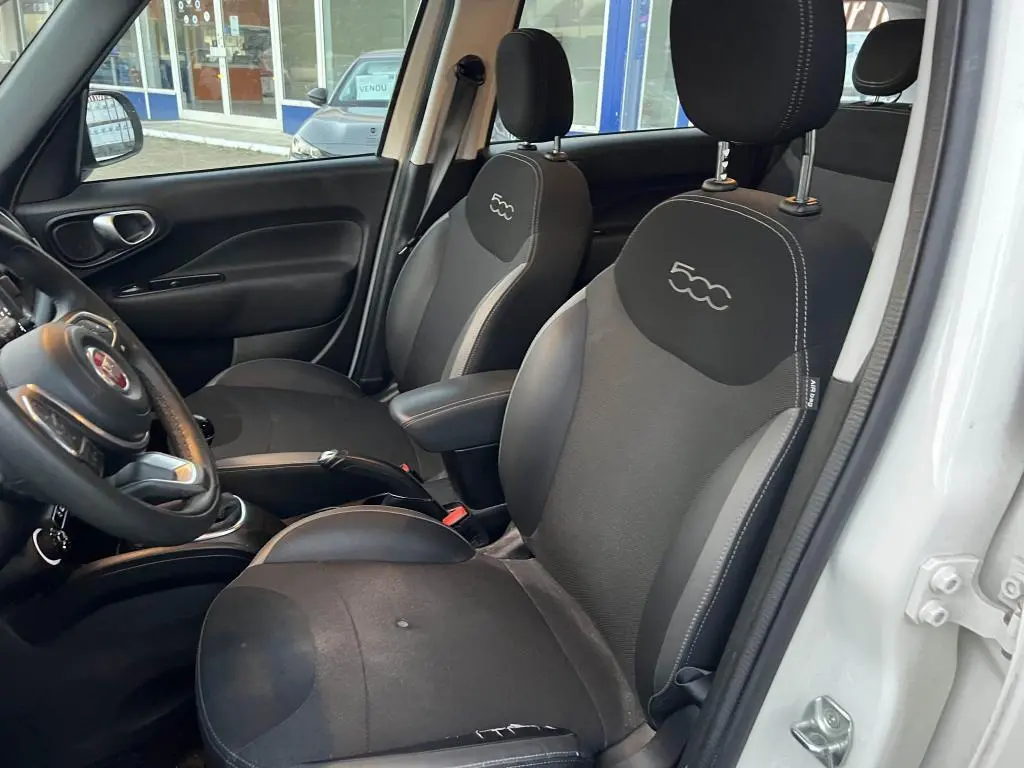 Vue intérieure côté conducteur de la Fiat 500L 2017 montrant les sièges noirs avec logo 500 brodé sur les appuie-têtes.