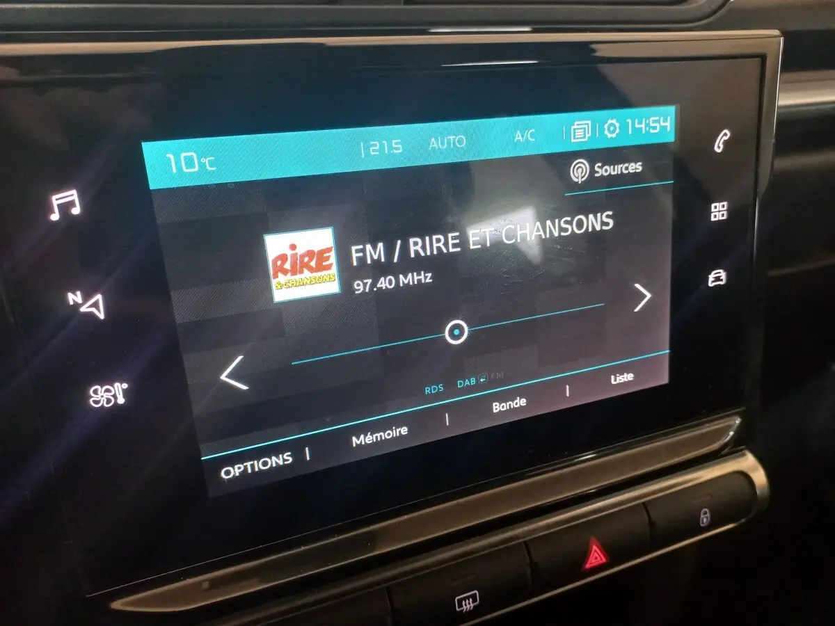 Écran tactile central de la Citroën C3 2024 affichant la radio FM sur fond noir, vue rapprochée intérieure.