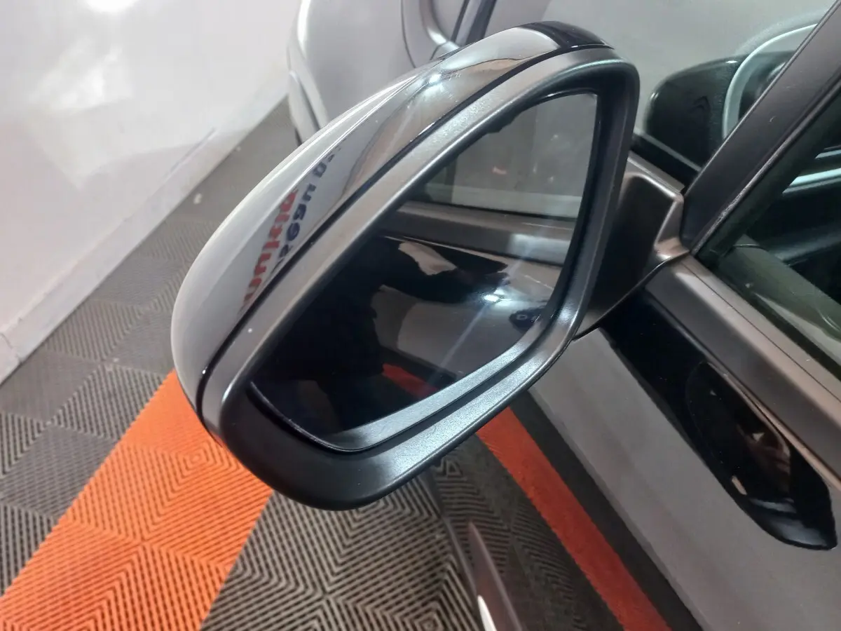 Rétroviseur extérieur droit noir brillant de la Citroën C3 2024, avec caméra intégrée et carrosserie noire visible en reflet.