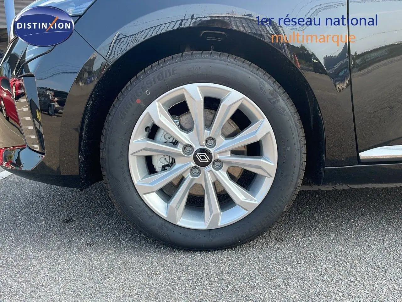 Gros plan sur la roue avant gauche de la Renault Clio noire étoile métal, mettant en valeur la jante alliage et le logo Renault central.