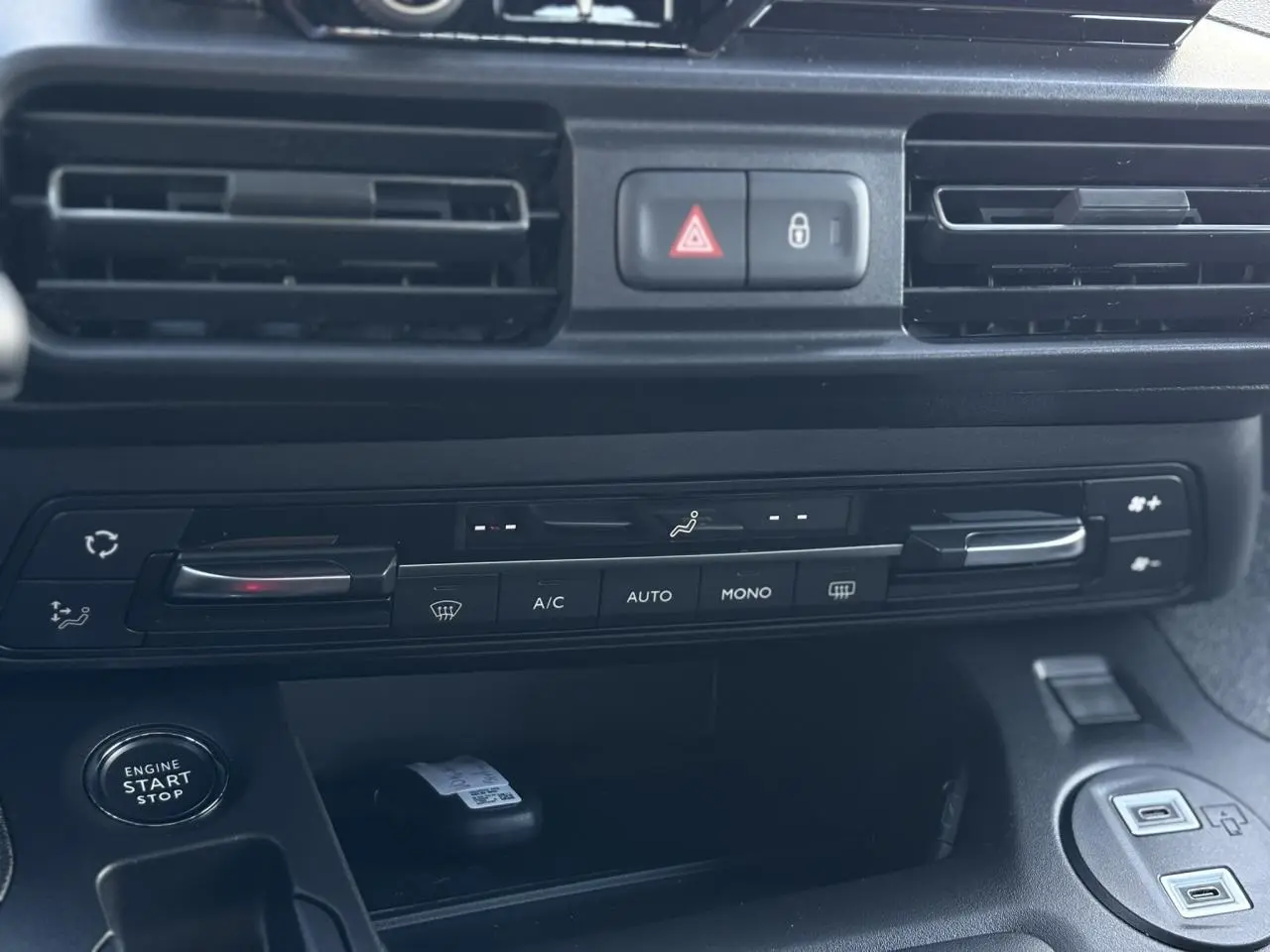 Vue rapprochée de la console centrale noire du Citroën Berlingo Multispace 2025 avec commandes climatisation et bouton start-stop.
