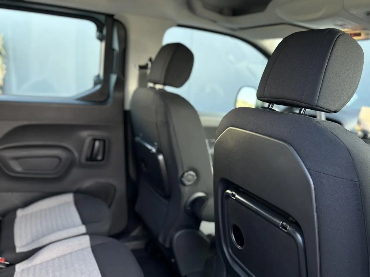 Intérieur du Citroën Berlingo Multispace bleu, vue sur les sièges arrière avec tablettes aviation rabattables.