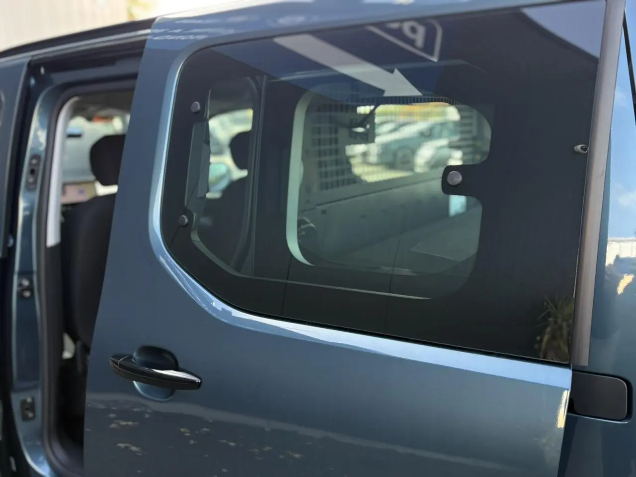 Porte latérale coulissante droite bleue du Citroën Berlingo Multispace 2025, vue rapprochée avec intérieur partiellement visible.