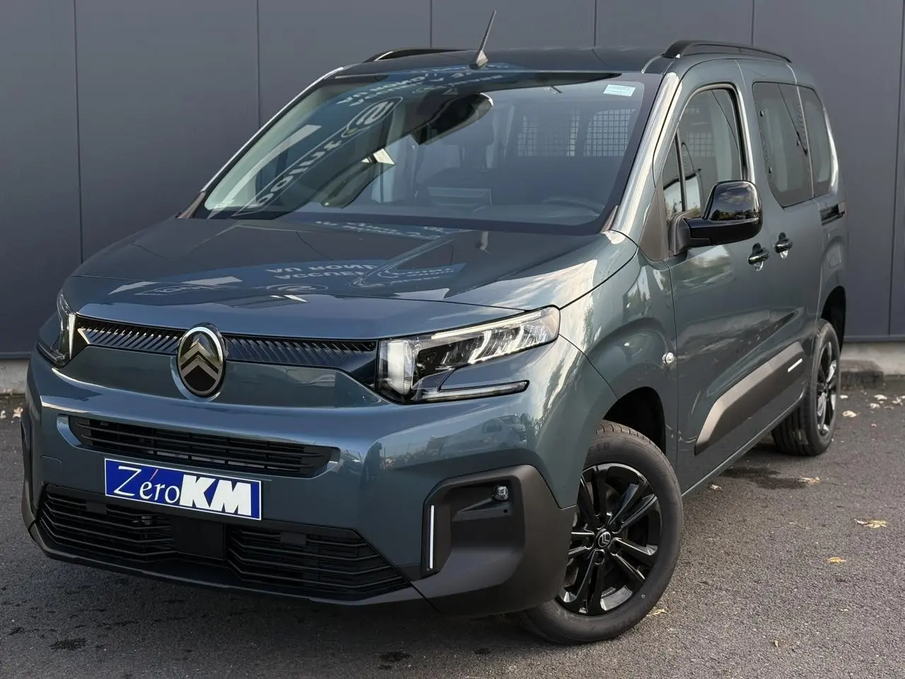 Vue 3/4 avant droit du Citroën Berlingo Multispace bleu métallisé avec jantes alliage noires et barres de toit.