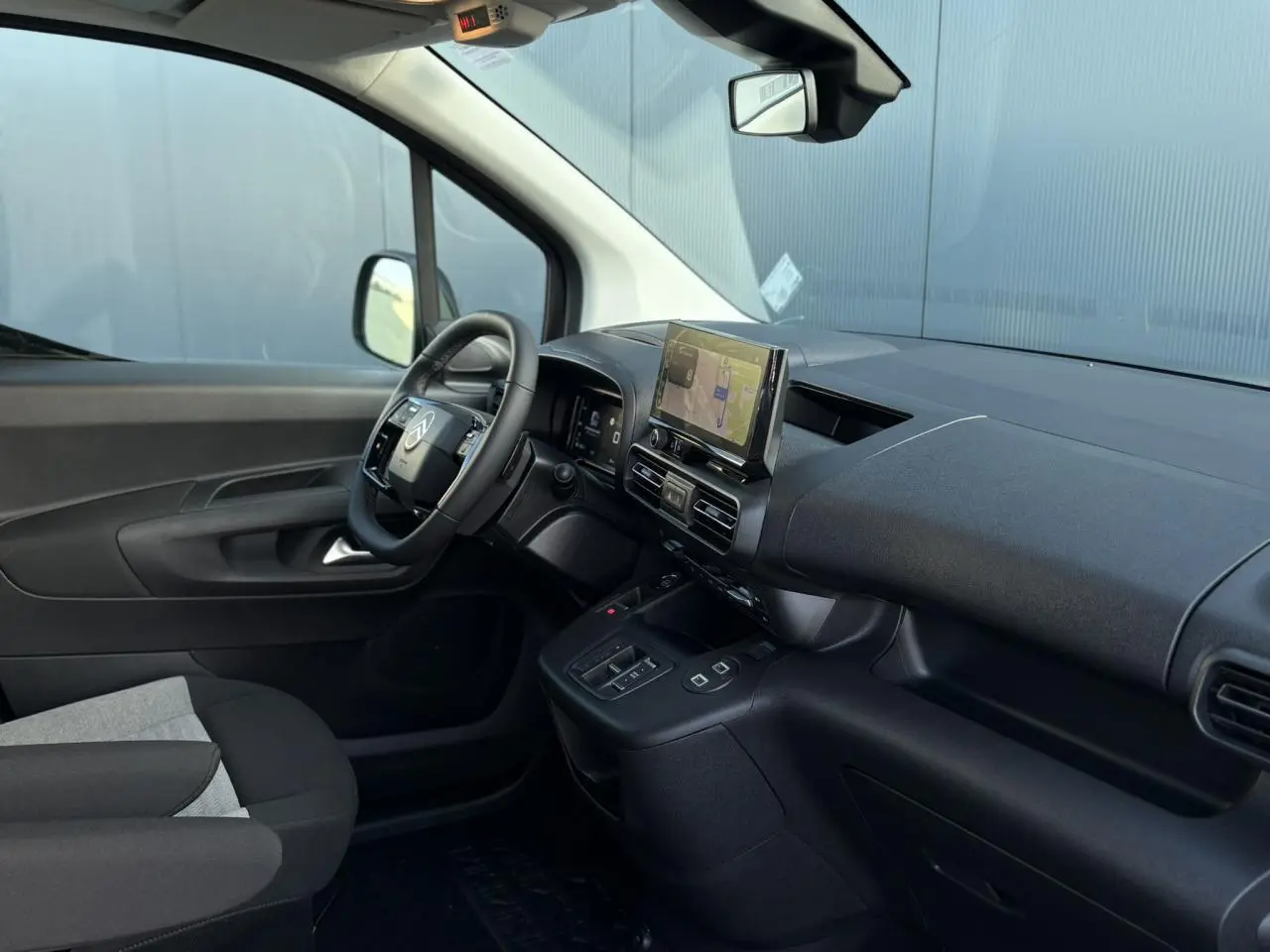 Vue intérieure côté conducteur du Citroën Berlingo Multispace 2025, tableau de bord noir avec écran tactile et volant multifonctions.