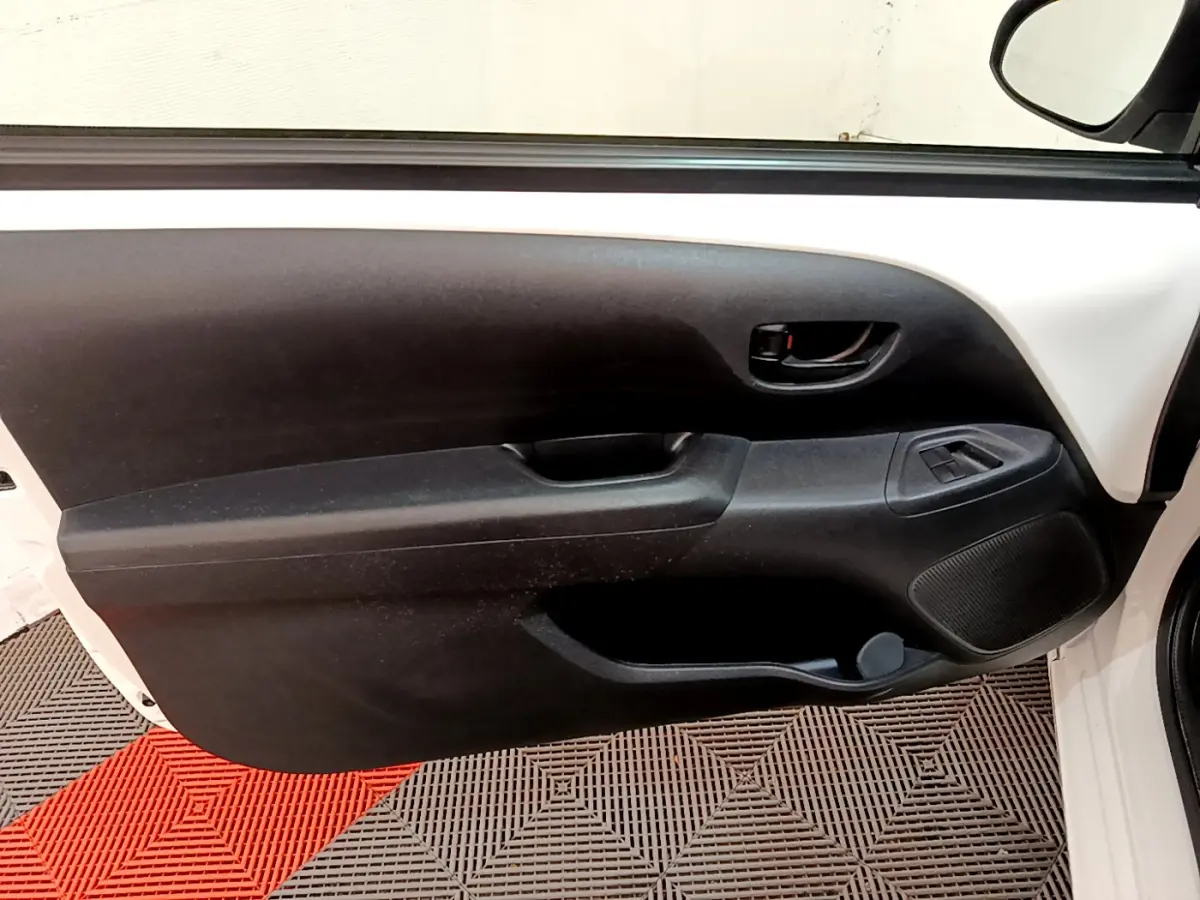Vue intérieure côté gauche de la porte avant blanche d'une Citroën C1 2020 avec panneau noir et commandes de vitres.