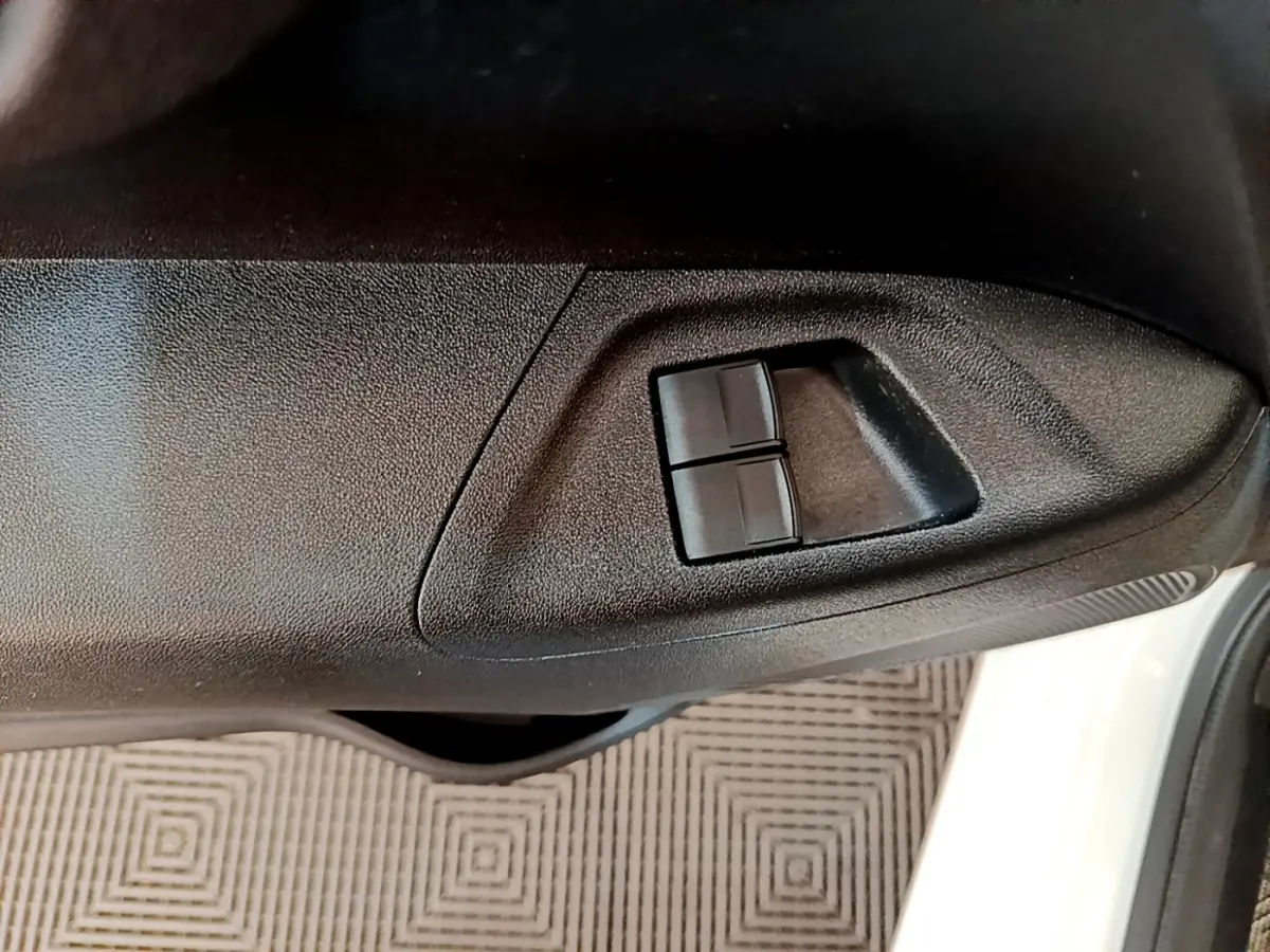 Gros plan sur les commandes des vitres électriques côté conducteur d’une Citroën C1 blanche, porte ouverte.